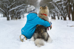 boy hugging dog in the snow in winter